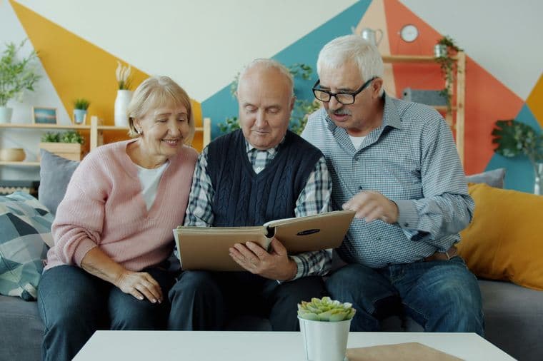 Tres personas de edad avanzada en una casa mirando un libro