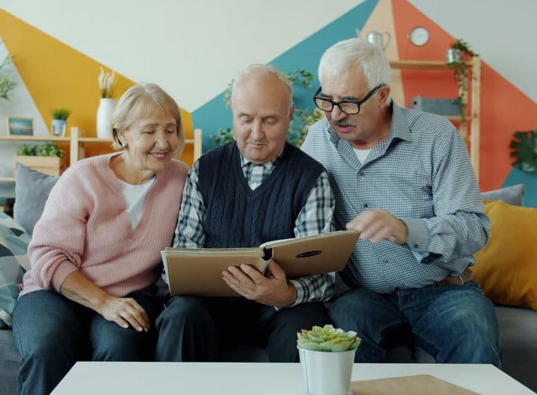 Tres personas de edad avanzada en una casa mirando un libro