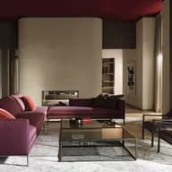 Modern living room with a purple sectional sofa, glass coffee table, dark wood built-ins, backlit shelves, and a curved beige fireplace wall.