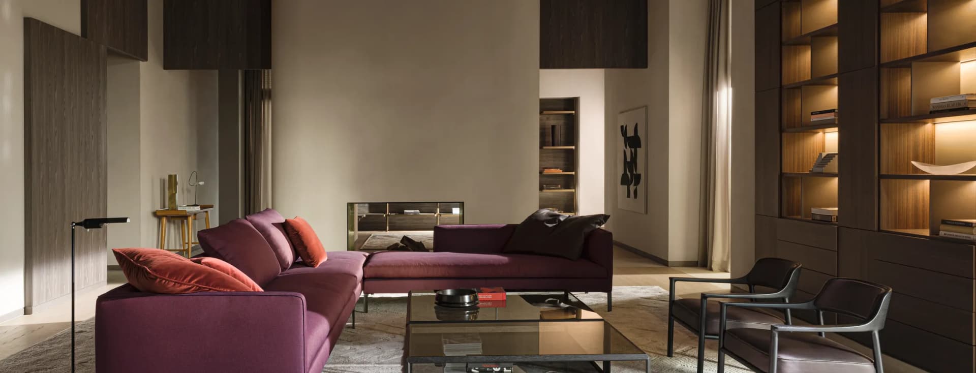 Modern living room with a purple sectional sofa, glass coffee table, dark wood built-ins, backlit shelves, and a curved beige fireplace wall.