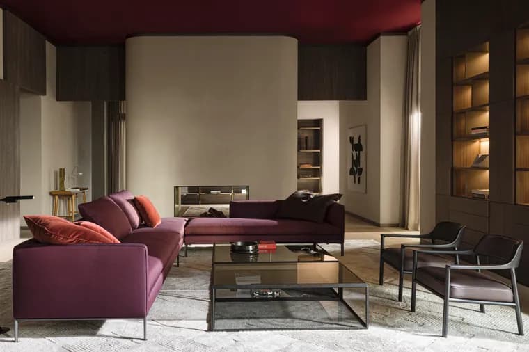 Modern living room with a purple sectional sofa, glass coffee table, dark wood built-ins, backlit shelves, and a curved beige fireplace wall.