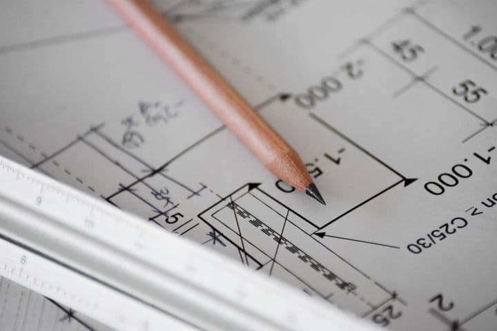 Close-up view of an architectural drawing with measurements and dimensions, showing a wooden pencil and metal ruler on the technical plan