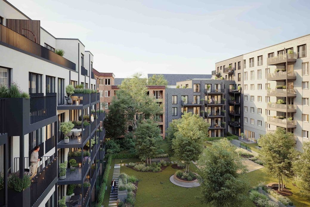 Modern apartment complex with multiple buildings, balconies, and a central green courtyard featuring trees and a walkway.