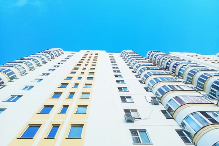 Gebäude von unten gesehen, sehr hoch, mit vielen Stockwerken und Fenstern ohne Balkone.