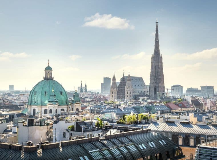 Property prices Vienna: Aerial view of the historic 1st district showing prestigious St. Peter's Church dome and St. Stephen's Cathedral among high-value rooftop properties and modern office buildings, reflecting the premium real estate market in Vienna's city center
