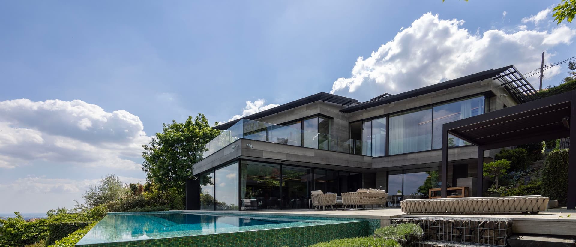 Minimál stílusú családi ház a budai hegyekben, a Széchenyi hegyen, modern kőburkolattal, infinity medencével, elvehetetlen panorámával.