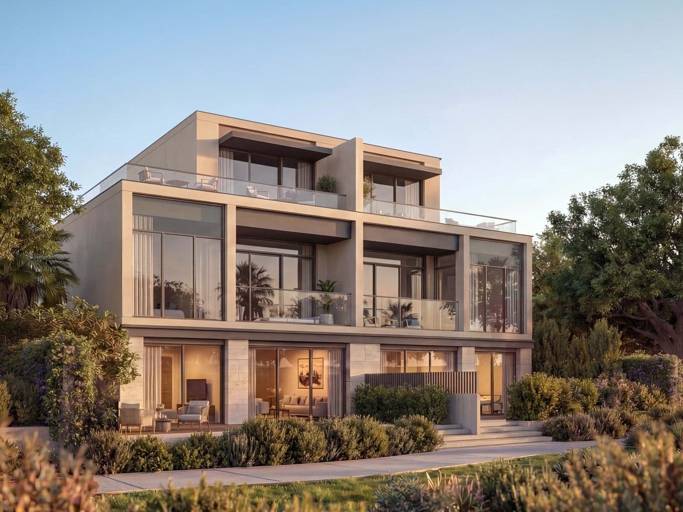 Modern three-story house with large windows and balconies, surrounded by lush greenery and trees, under a clear sky.
