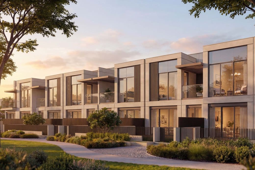 Modern row of glass-fronted townhouses at sunset, with landscaped greenery and a winding path in the foreground.