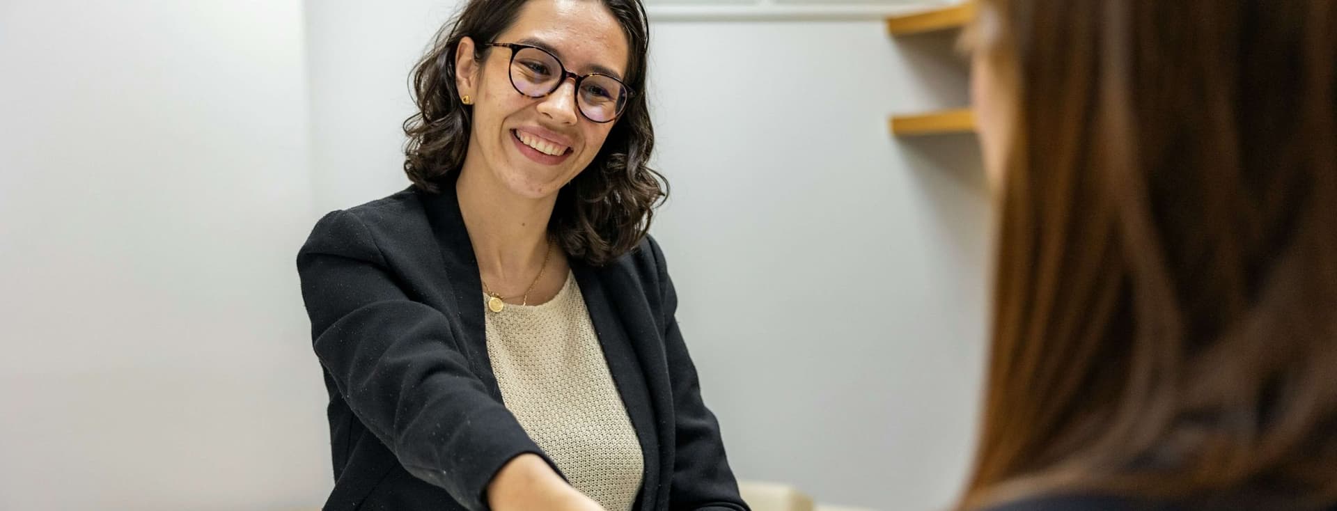 Una mujer estrechando la mano de otra en una entrevista de trabajo