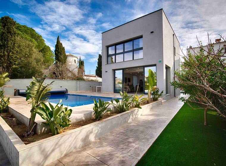 View of a modern house with swimming pool at its entrance, garden around it and blue skies with clouds