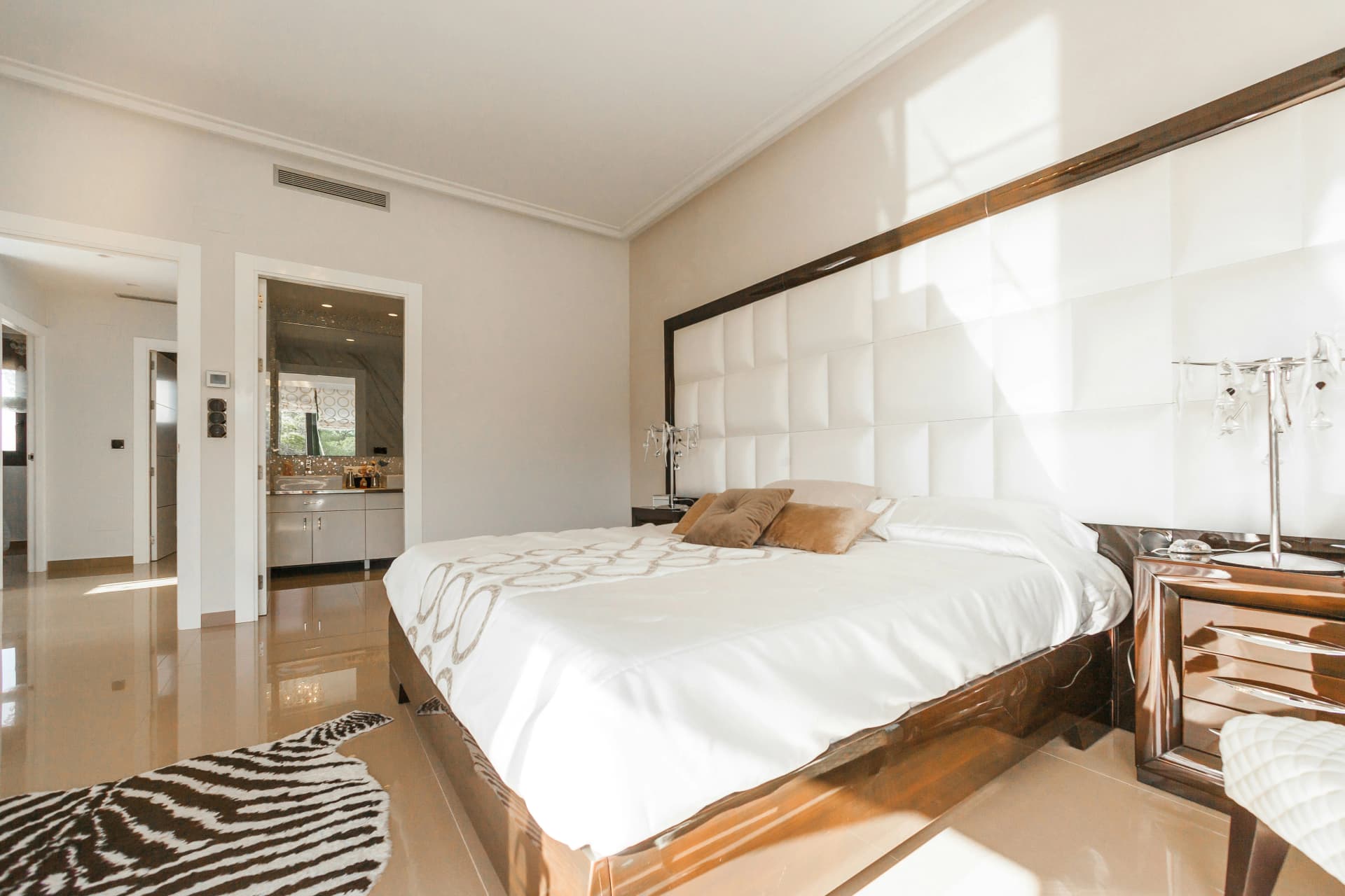 Dormitorio grande con una cama de matrimonio y un baño al fondo