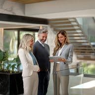 A real estate agent shows a couple a property on a tablet in a modern home.