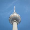 Low-angle view of the Berlin TV Tower against a clear blue sky. The tower's spherical observation deck is highlighted.