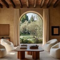 Bright and well-appointed living room in a house for sale, featuring beige walls, dark wooden beams, and arched windows