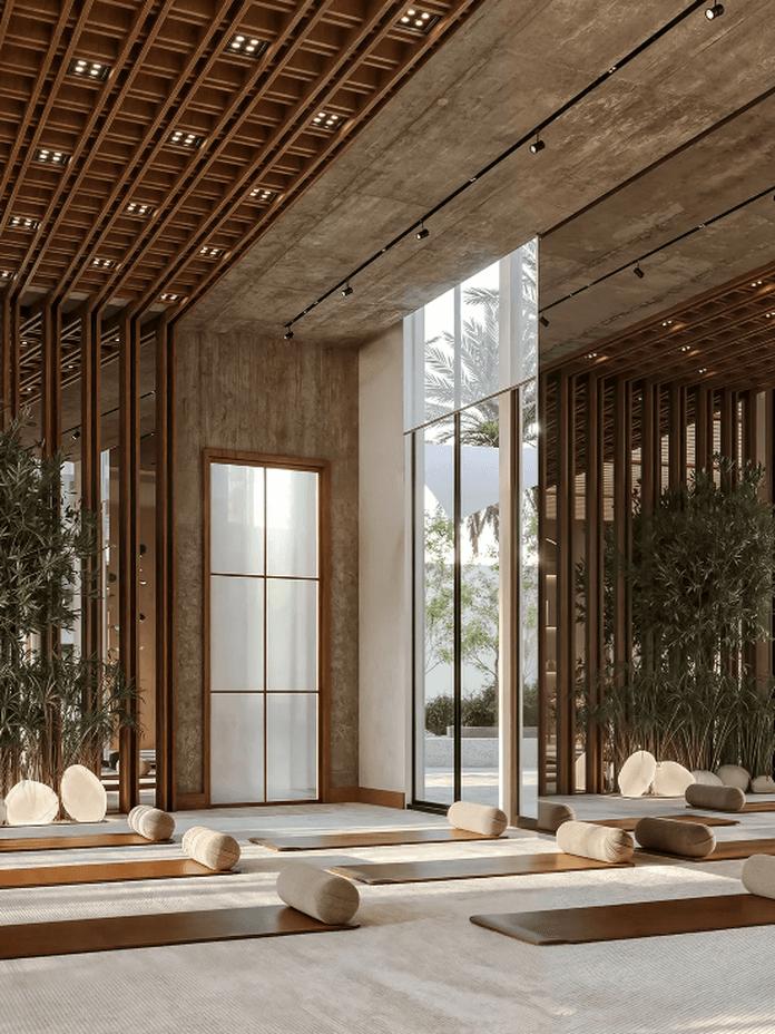 A serene yoga studio with wooden accents, large windows, floor cushions, and bolsters, surrounded by greenery and soft natural light.