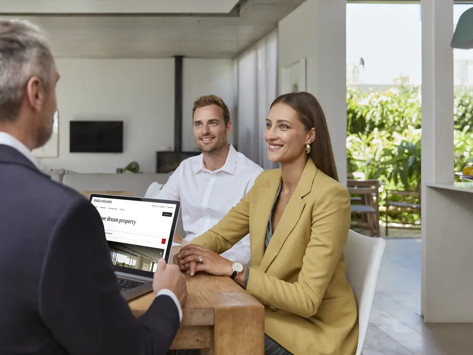 Couple meeting with a mortgage advisor to discuss property financing options in a modern, bright home office setting.