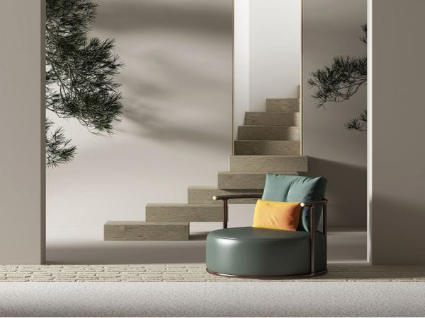 Interior modern amb una cadira verda, un coixí taronja i escales de pedra que pugen a través d'una porta. Una branca d'arbre penja al fons.