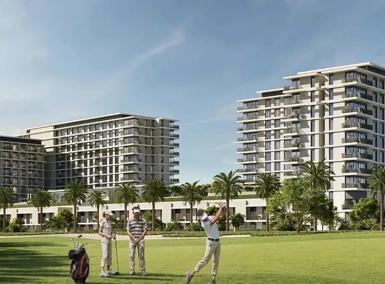 Three people playing golf on a lush green course with tall modern buildings and palm trees in the background under a clear blue sky.