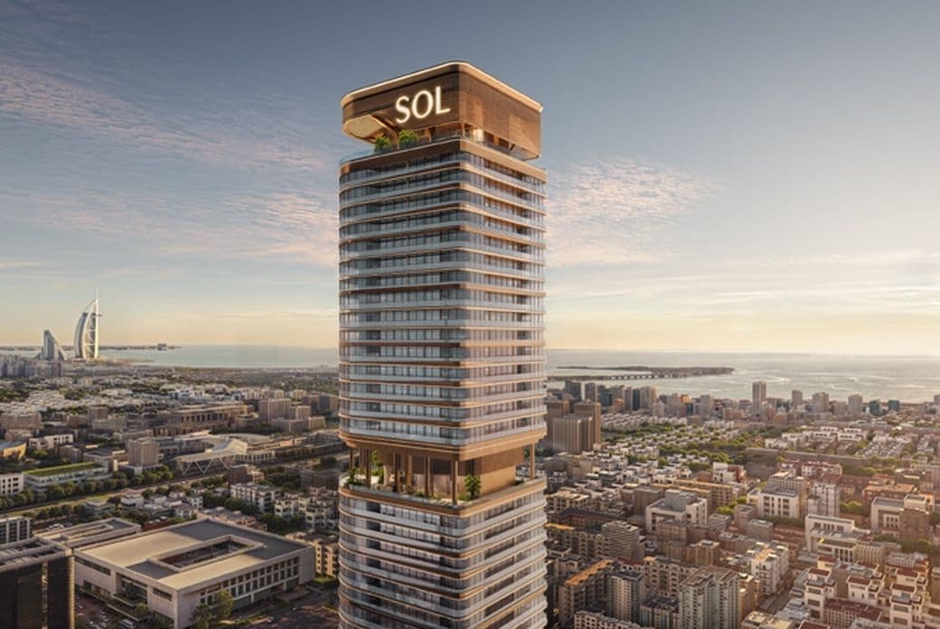 Tall modern skyscraper labeled "SOL" with terraces, overlooking a cityscape and ocean, with a famous sail-shaped hotel in the background.