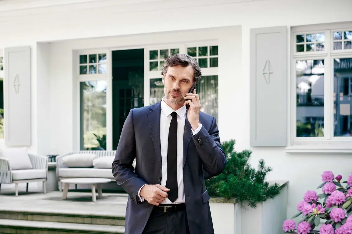 Man in front of a property while having a call