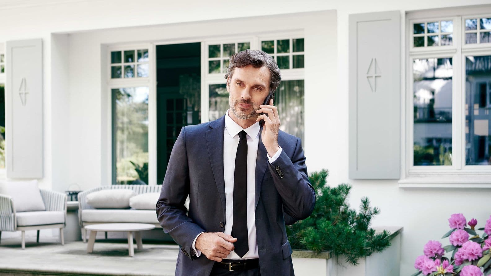 Man in front of a property while having a call
