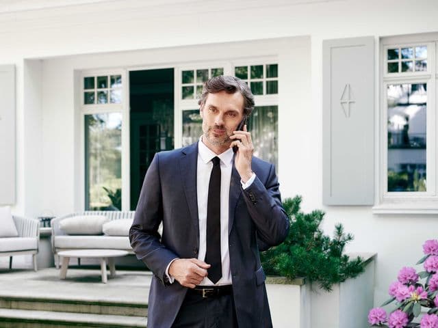 Man in front of a property while having a call