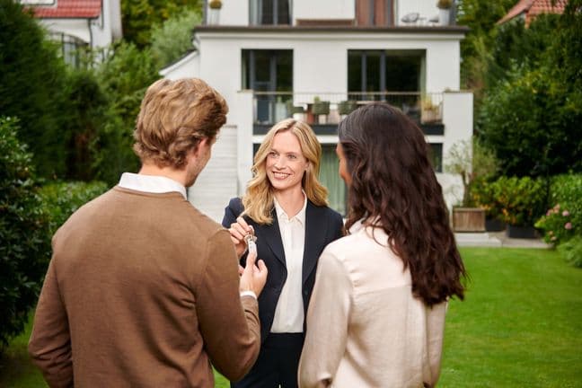 Handing over keys to customers standing in front of the house