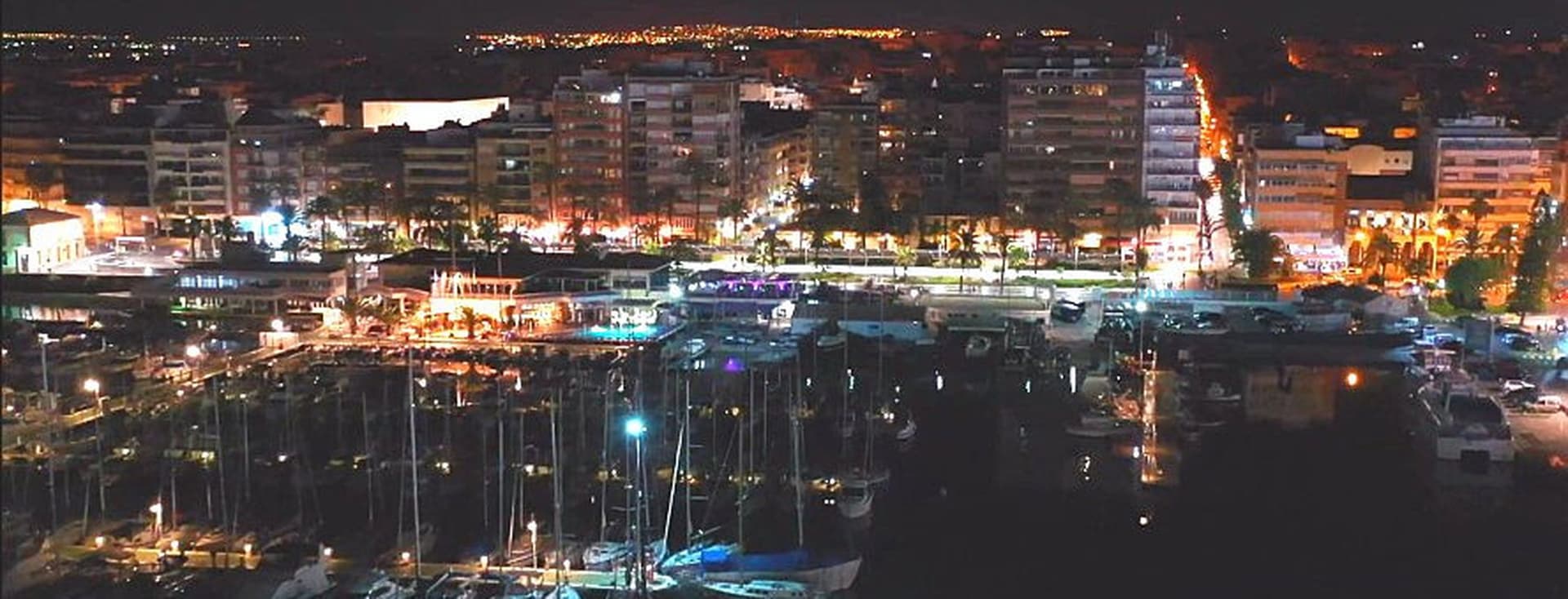 Vista nocturna del port de Torrevella amb vaixells i edificis prop del port.