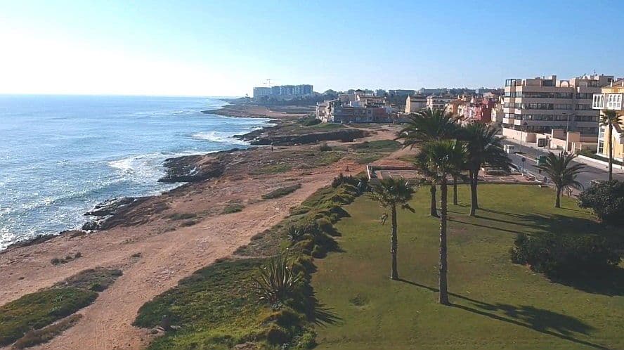 Vista panoràmica de la Veleta amb la seva platja i mar, palmeres i edificis.