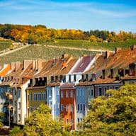 Bunte Altstadthäuser mit Blick auf Weinberge und Kirchturm in Würzburg – herbstliche Stadtansicht mit fränkischem Flair